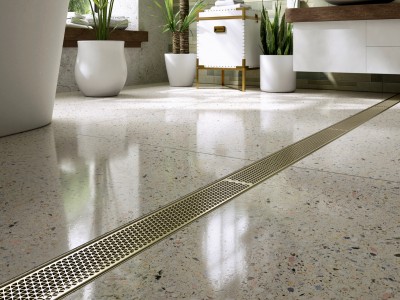 Brass stainless steel linear drain running lengthways across modern bathroom